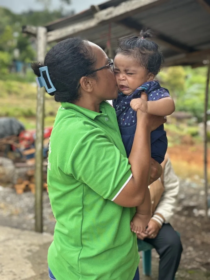 Seorang ibu menggendong anaknya di sela kegiatan bersama posyandu.