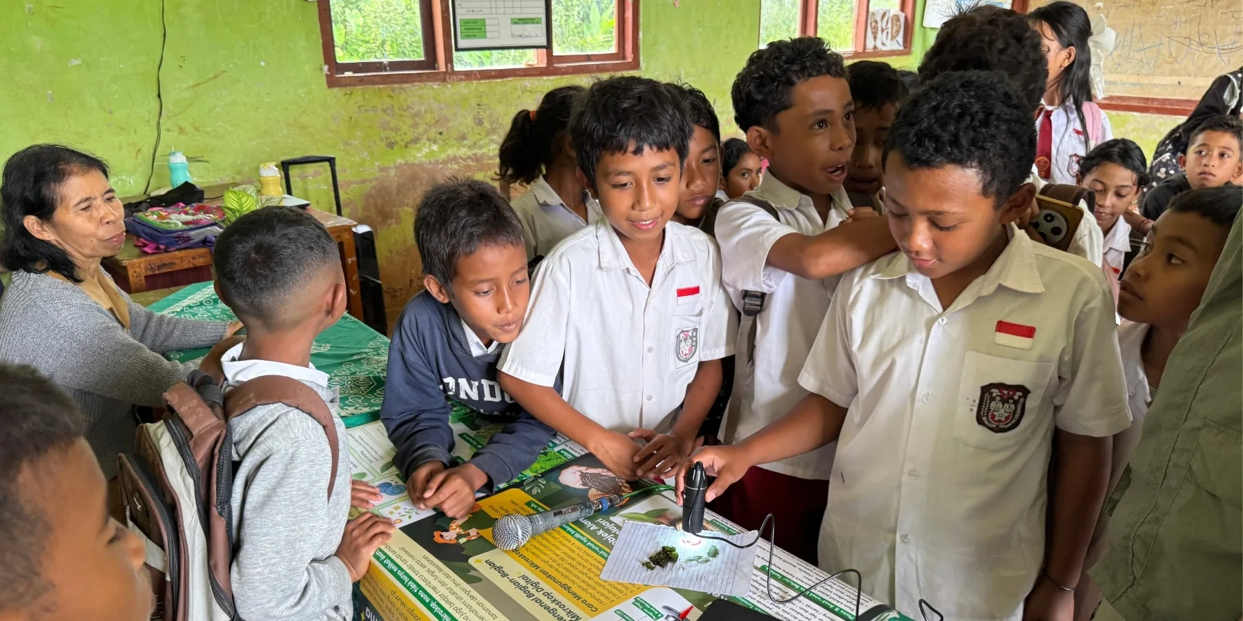 Siswa sekolah dasar mengamati daun dengan mikroskop digital.